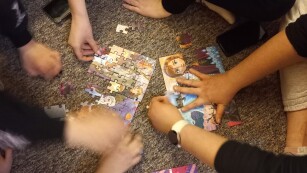 Układanie puzzli, ręce młodzieży układające puzzle