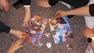 Układanie puzli, ręce młodzieży układające puzzle