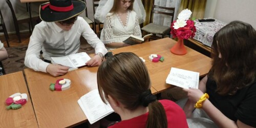 czytanie wesela, młodzież siedzi przy stole i czyta 